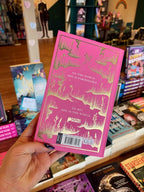 A hand holds a copy of 'Believe Me' by Tahereh Mafi, with gold foil artwork and text on the back cover in a bookstore setting, surrounded by other books on shelves.