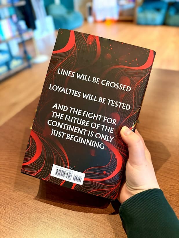 A hand holding the back of a copy of the hardcover edition of 'Broken Dove' by Dani Francis, featuring a black and red cover with large white text.