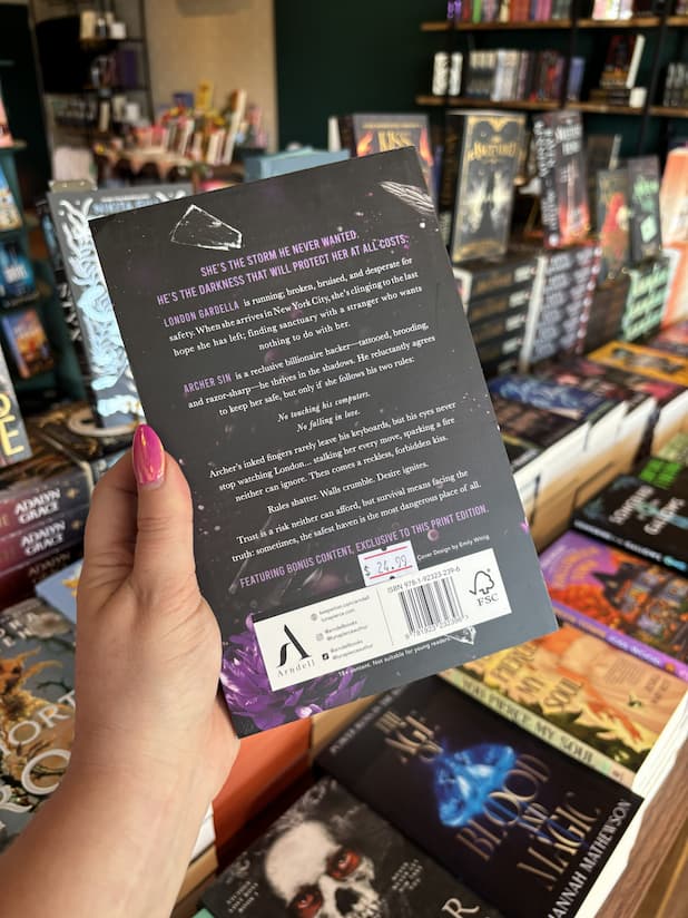 A hand with pink nail polish holds the back of a copy of 'Dangerous Haven' by Luna Pierce, featuring a dark grey background with purple and white text.