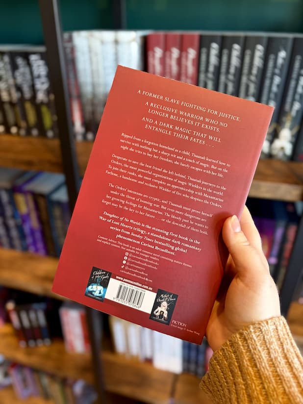 A hand holding the back of a paperback copy of 'Daughter of No Worlds', featuring a black background and white text.