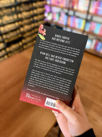 A hand holding the back of a paperback copy of 'Devil' by Sierra Simone, featuring a black background that fades to red at the bottom and white text.