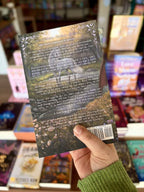 A hand holding a copy of 'Foundling' by S.E. Wendel featuring a fantasy forest with a unicorn by a river and white text.