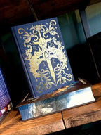 Book cover of 'Fury Bound' by Sable Sorensen featuring a dark blue cover with gold detailing of two head wolf heads holding a gem on top of a sword.