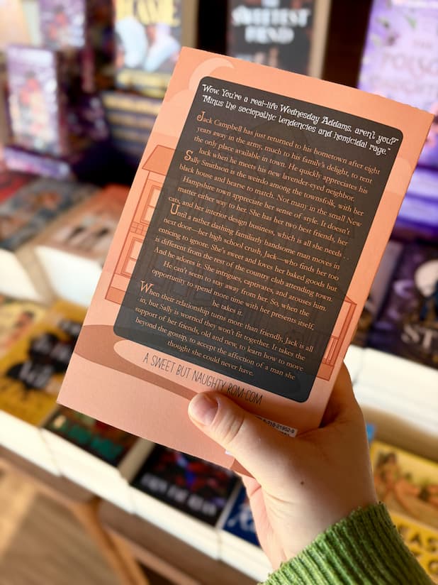 A hand holding the back of a copy of 'Her Favorite Jack-o-Lantern' with an orange and black background, and orange and white text.