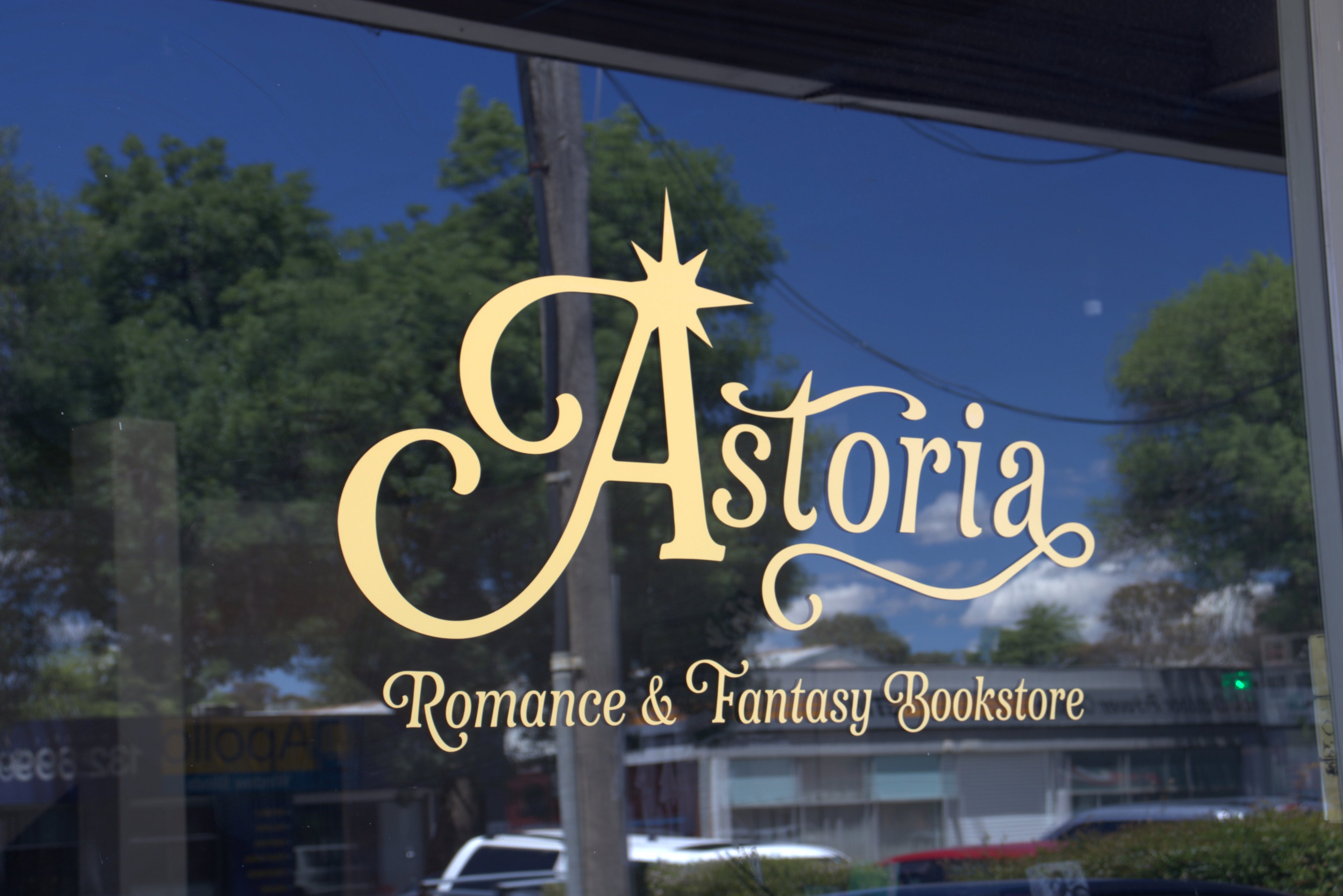 Window with 'Astoria Romance & Fantasy Bookstore' logo and text.