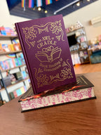 A small stack of the special edition cover of 'Kiss of the Black Flame' by Helen Scheuerer, showing the hard cover under the dust jacket, a maroon cover with gold detailing, and patterned pink-and-white sprayed edges.