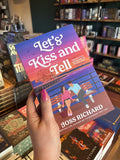A hand with pink nail polish holds a copy for 'Let's Kiss and Tell' by Joss Richard, featuring an illustrated couple sitting on a bench by the water at a pier with a ferris wheel and colorful sunset sky.
