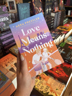 A hand with nude nail polish holds a copy of 'Love Means Nothing' by Abra Pressler, featuring a colorful illustrated tennis court scene with two players, tennis rackets, and the Eiffel Tower in the background.