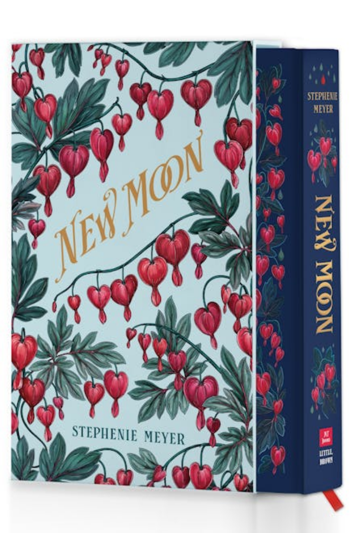 The hardcover collector's edtion of 'New Moon' Stephanie Meyer, featuring a light blue cover decorated with red heart-shaped flowers and green leaves, shown next to its navy blue spine.