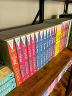 A row of colorful paperback books in a series titled 'Off Campus' by Elle Kennedy displayed on a wooden bookshelf. The spines show different colored chapters: orange, pink, red, blue, purple, yellow, and green.