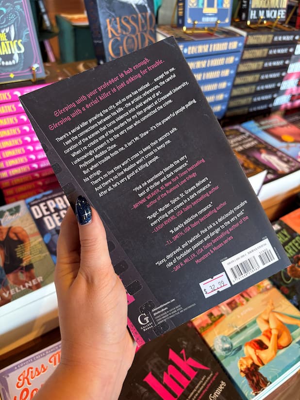 A hand holding the back cover of a 'Pink Ink' by Avina St. Graves a professor and student romance