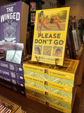 A stack of the book for 'Please Don't Go' by E. Salvador, alternating spine and digitally sprayed edge, the cover features a retro-style illustrated design with a yellow background, green title text, and vintage photographs of the main characters and baseball elements, in front of a blurry bookshelf full of books.