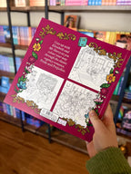 A hand holding the back of a copy of 'Pride and Prejudice Colouring Book' featuring a dark pink background with a floral border and black and white illustrated pages.