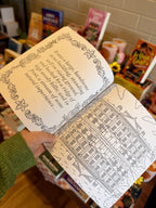 A hand holding an open copy of 'Pride and Prejudice Colouring Book' featuring an illustrated multistory house and a quote.