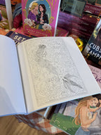 An open copy of 'Romantasy Coloring Book' with an illustration of a mermaid.