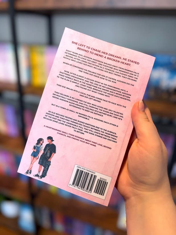 A hand holding the back of a copy of 'Second Chances' by Sommer-Lee Deaves, featuring an illustration of a man and a woman as teenagers on a pastel pink background, and dark text.