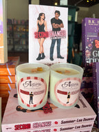 Two 'Astoria Second Chances' soy candles by Sommer-Lee Deaves displayed on top of their book packaging, with a matching book cover standing behind them in a retail setting.