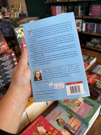 A hand with pink nail polish holding the back of a copy of 'Set the Record Straight' by Hannah Bonam-Young, featuring a light blue background and dark blue text. 