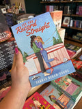 A hand with pink nail polish holding a copy of 'Set the Record Straight' by Hannah Bonam-Young, featuring an illustrated female couple embracing in a kiss outside an ice skating rink.