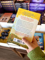 A hand holding the back of a copy of 'Something About September' by Julia McKay, featuring an autumnal background with black and red text.