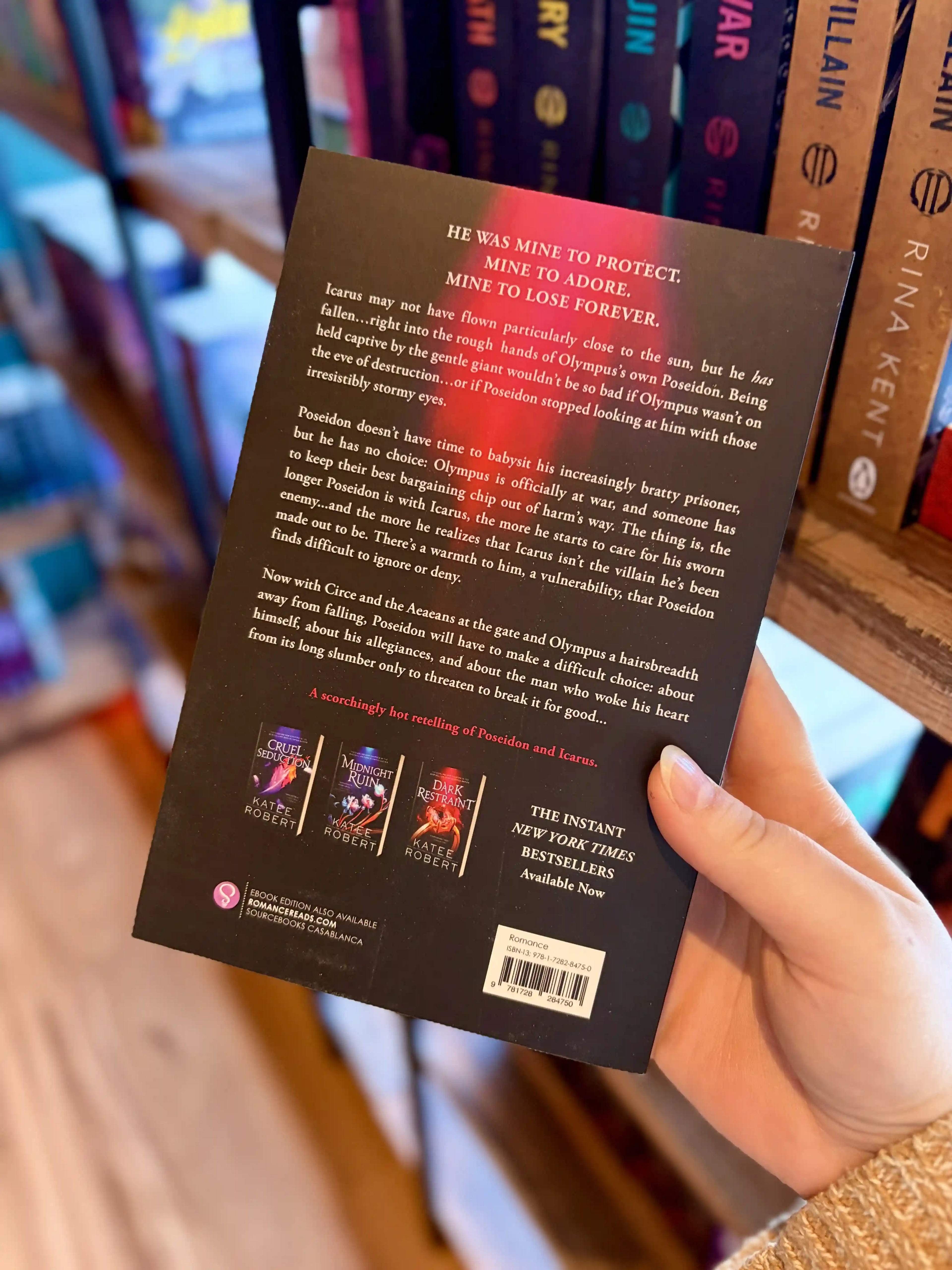 A hand holding the back of a paperback copy of the book 'Sweet Obsession' by Katee Robert. It is featuring a glowing pink and red spiral shell on a dark background with white and green title text.