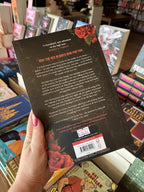 A hand with pink nail polish holds the back of the book 'Tempest' by Victoria Aveyard, featuring a dark background with illustrated roses and white and red text.