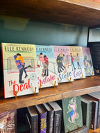 Five paperback books by Elle Kennedy displayed on a wooden bookshelf, featuring colorful illustrations of people playing sports on the covers.
