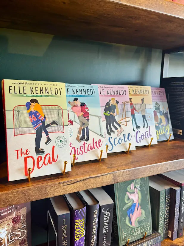 Five paperback books by Elle Kennedy displayed on a wooden bookshelf, featuring colorful illustrations of people playing sports on the covers.