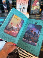 A hand with pink nail polish holds a copy of the special edition version of 'The Fine Print' by Lauren Asher in a bookstore with other books blurry in the background. The back end pages feature two illustrations of the main characters. On one side they sit on the floor eating from boxes of takeaway, on the other side they sit together on a swing chair staring deeply into each others eyes with a big castle and fireworks in the background.