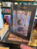 A stack of boxed jigsaw puzzles titled "The Knight & The Moth" by Reverie Puzzles, showing an illustrated scene of Sybil, Rory and Bartholomew the gargoyle set within the hauntingly beautiful Aisling Cathedral of Traum, with the Omens' stone objects floating in the spring. 