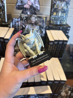 A hand with pink nail polish holding a gargoyle figurine. It sits upon a platform that reads 'The Gargoyle' in large text and 'The Stonewater Kingdom' in smaller text under that.