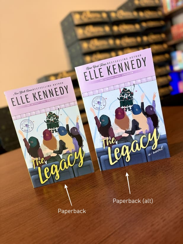 Two copies of the paperback book 'The Legacy' by Elle Kennedy are displayed side-by-side on a wooden table, with the one on the right sitting taller. The cover is an illustration of four women waving at men on an ice rink.