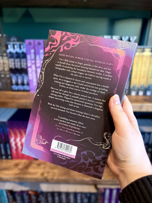 A hand holding the back of a copy of 'The Thread That Binds Us' by Helena Potter, featuring ornate decorative elements against a black and purple background, and white text.