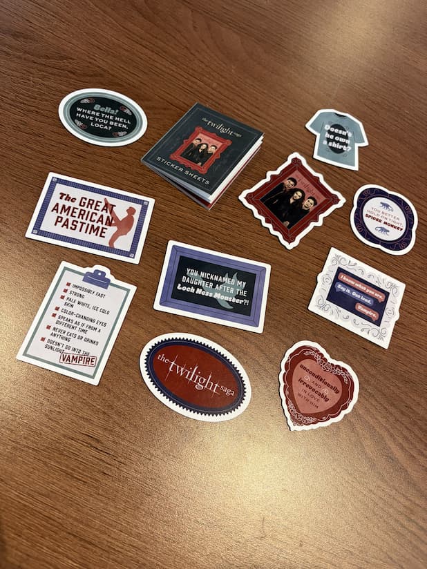 A collection of Twilight-themed magnets, and a small sticker booklet, arranged on a wooden tabletop.