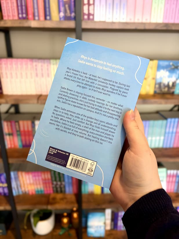 A hand holding the back of a copy of 'Unsteady' with white and blue text on a light blue background.