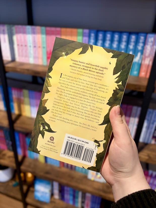 A hand holding the back of a copy of 'You Pierce My Soul' with a yellow background, green leaves, and brown text.