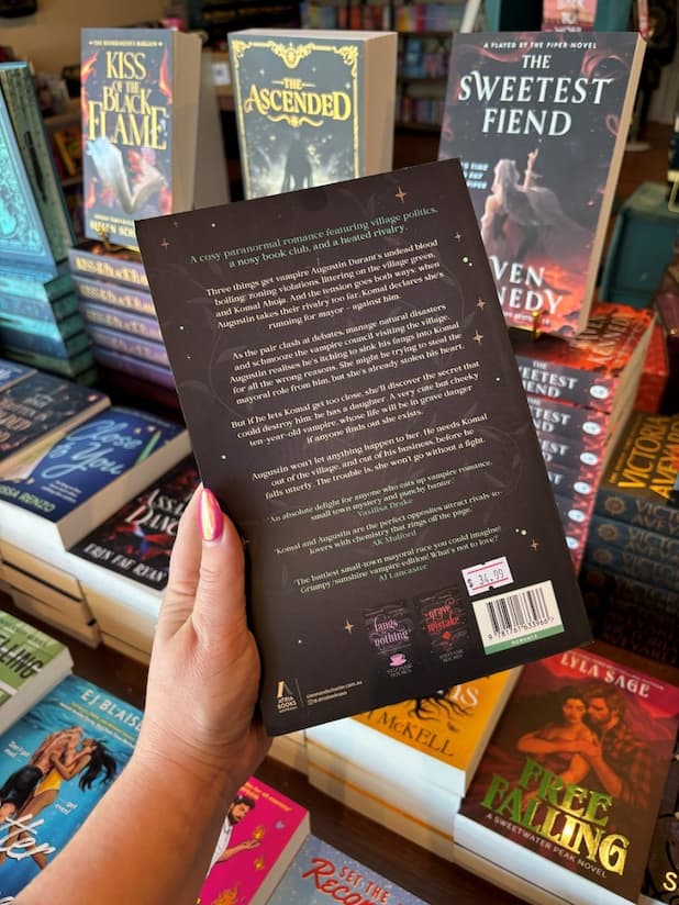 A hand with pink nail polish holds the back of a copy of 'You're So Vein' by Steffanie Holmes, featuring a black cover with green vines and white text.