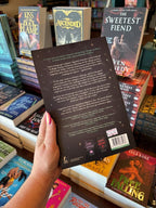 A hand with pink nail polish holds the back of a copy of 'You're So Vein' by Steffanie Holmes, featuring a black cover with green vines and white text.